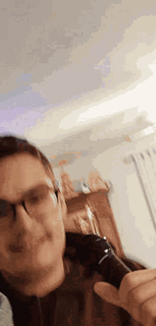 a man wearing glasses is holding a microphone in his hand in a living room .