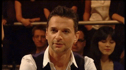 a man in a white shirt and black vest stands in front of a group of people