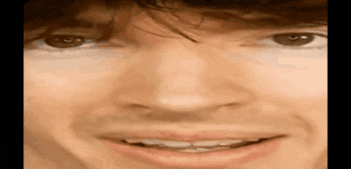 a close up of a man 's face with his mouth open and his eyes looking at the camera .