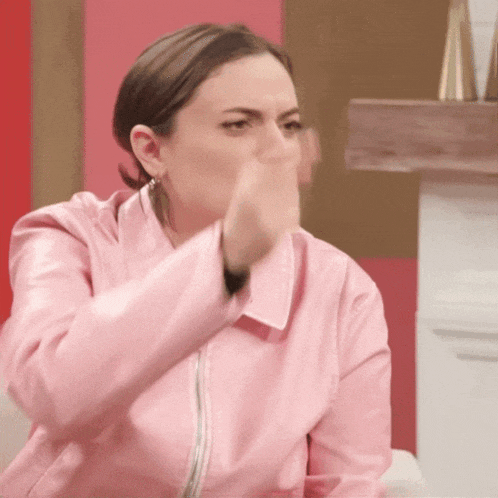 a woman wearing a pink leather jacket is making a funny face