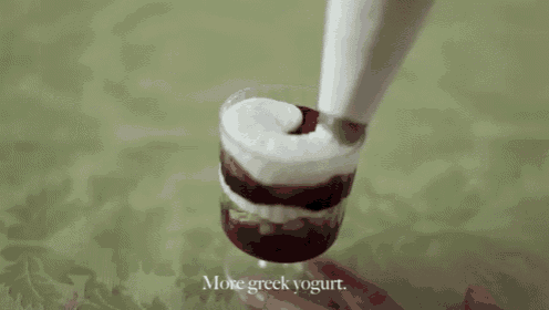 a cup of greek yogurt is being poured into a dessert