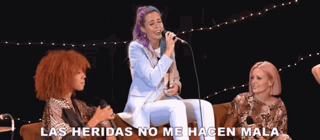a woman singing into a microphone with the words las heridas no me hacen mala written below her