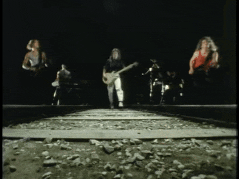 a group of people standing on train tracks playing guitars