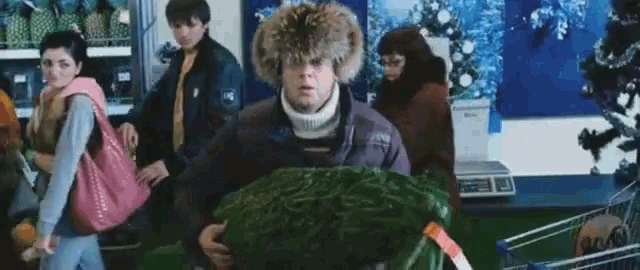 a man in a fur hat is carrying a christmas tree in a grocery store