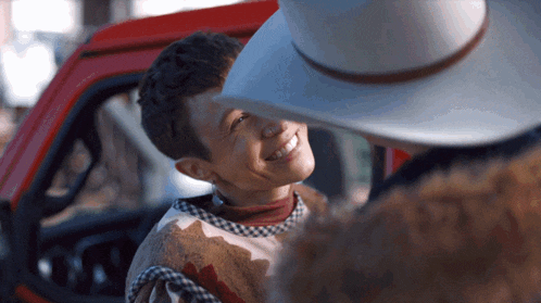 a man in a cowboy hat talks to a boy in a plaid sweater