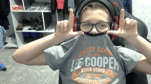 a boy wearing headphones and a lee cooper shirt makes a peace sign