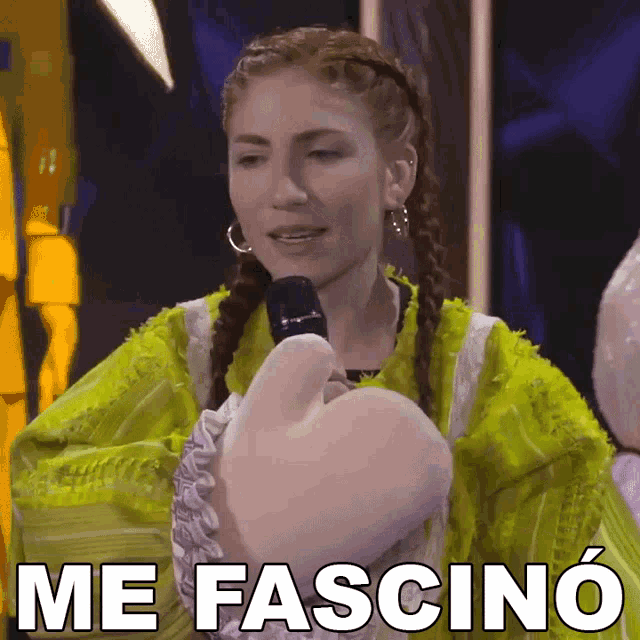 a woman in a green jacket is holding a microphone and says me fascina