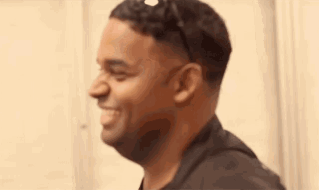 a man in a black suit is smiling and looking to the side .