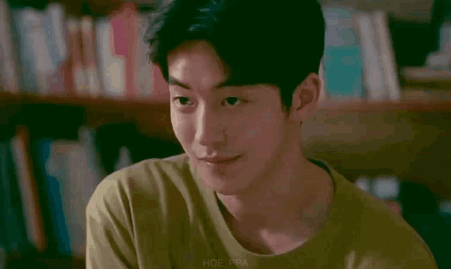 a young man in a green shirt is smiling with his eyes closed .