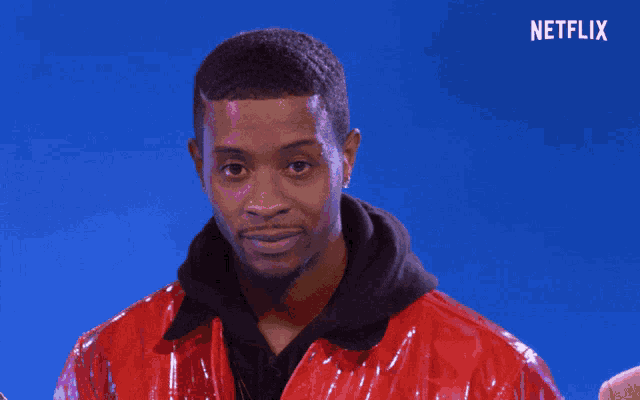 a man in a red jacket is standing in front of a blue background that says netflix on it
