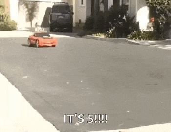 a red toy car is driving down a street with the words `` it 's 5 ! ''