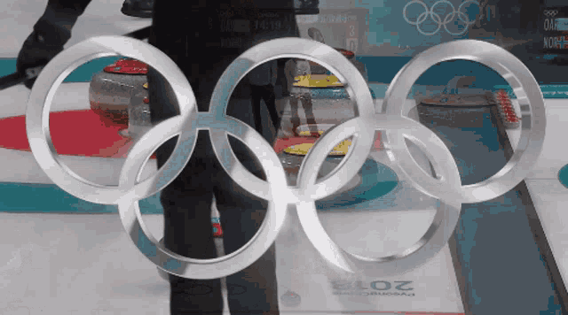 the olympic rings are displayed in front of the curling rink