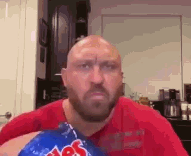 a bald man with a beard is holding a bag of potato chips in his hand .