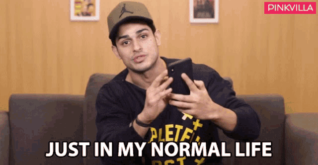 a man holding a cell phone with the words just in my normal life behind him