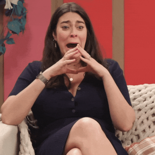 a woman sits on a couch with her mouth open