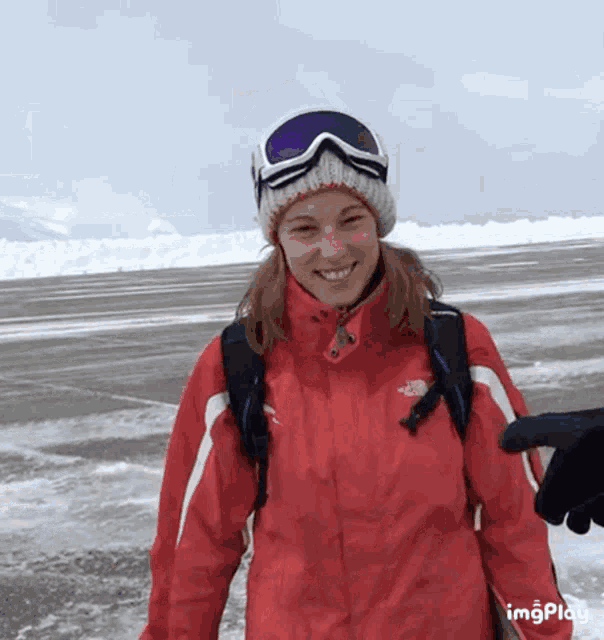 a woman wearing a red jacket with the north face on it