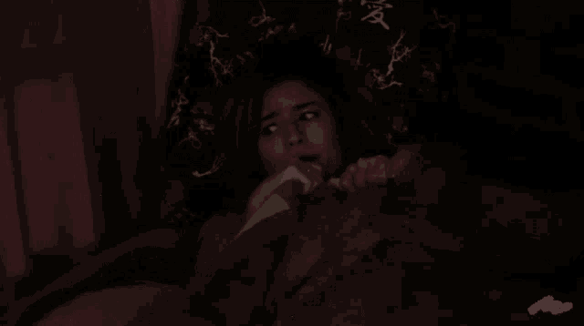 a person is laying on a bed in a dark room with a purple blanket .