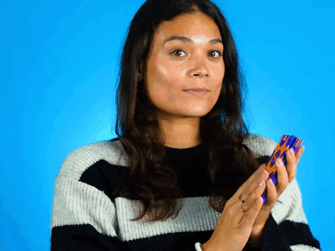 a woman wearing a black and white striped sweater is holding a colorful object in her hands