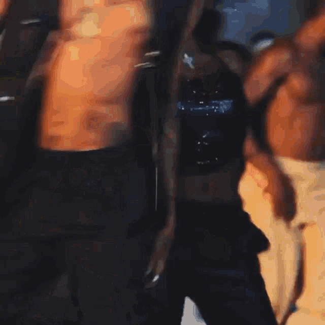 a woman in a black top and pants is standing next to a shirtless man in a room .