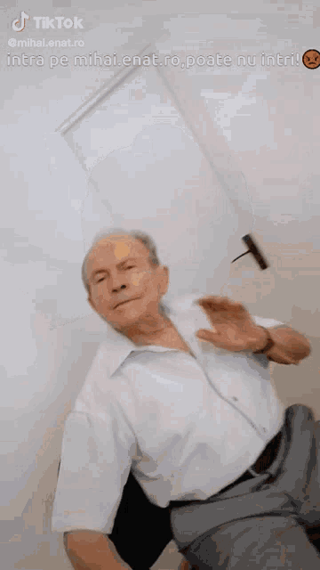 a man in a white shirt and gray pants is sitting in front of a door with a tiktok sticker on it