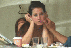 a woman is sitting at a table with a cup of coffee and glasses