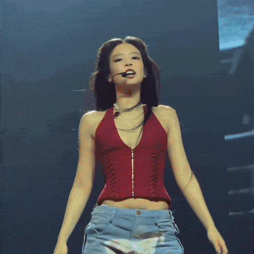 a woman in a red top is holding a microphone on a stage