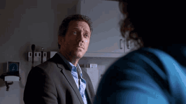 a man in a suit and tie talks to a woman in a blue jacket