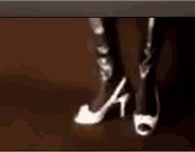 a woman wearing a pair of white high heels is standing on a brown surface .