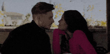 a man kisses a woman on the forehead while they look at each other