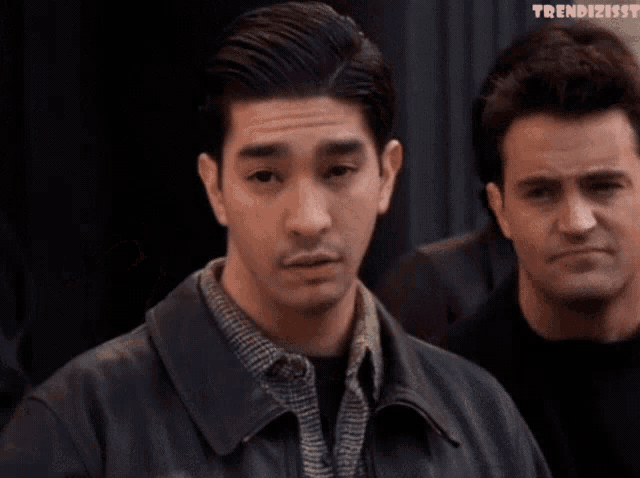 two men are standing next to each other and one is waving