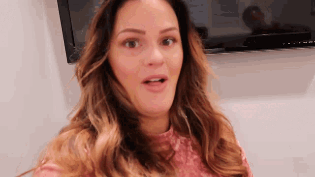 a woman with a surprised look on her face is standing in front of a flat screen tv