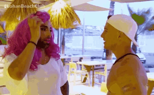 a man in a pink wig is talking to another man in a white hat ..