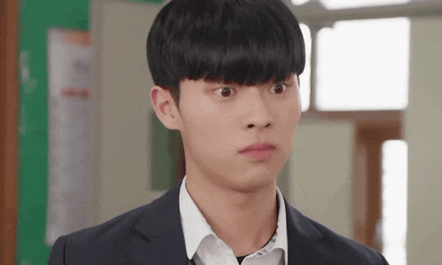 a young man in a suit is making a funny face in a classroom .