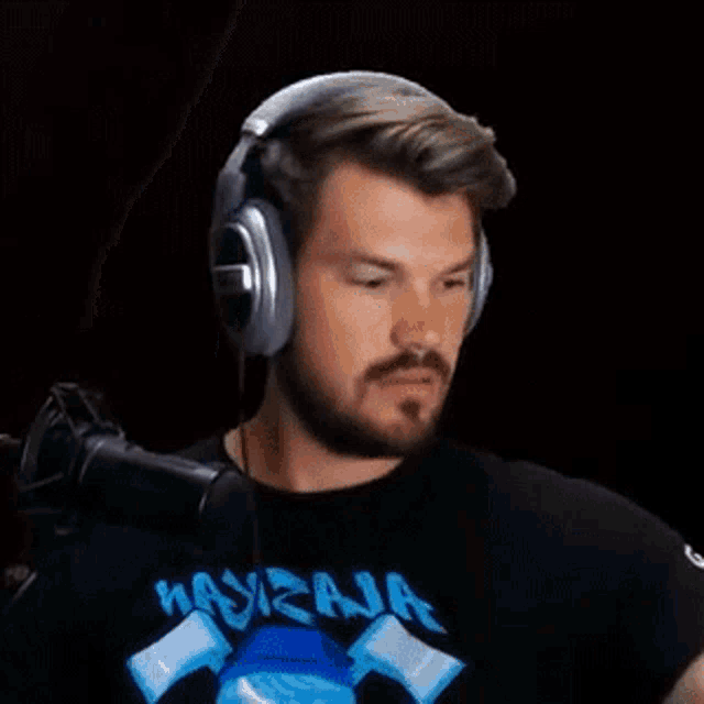 a man with a beard is wearing headphones and a t-shirt with a shark on it .