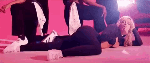 a woman is laying on her stomach on the floor while a group of people are standing around her .