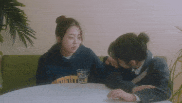 a man and a woman are sitting at a table and the man has a sweatshirt on that says university on it