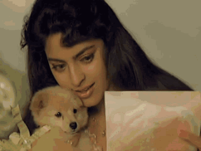 a woman holding a small puppy and a card