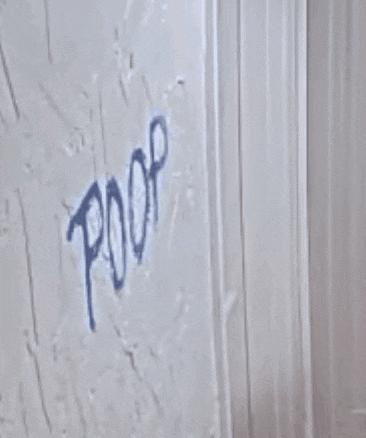 a man is peeking out from behind a wall that has the word poop written on it