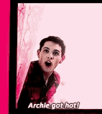 a young man in a plaid shirt is standing in front of a pink wall .