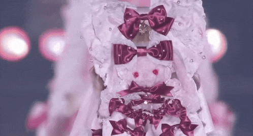 a woman wearing a pink dress with purple bows and a teddy bear .