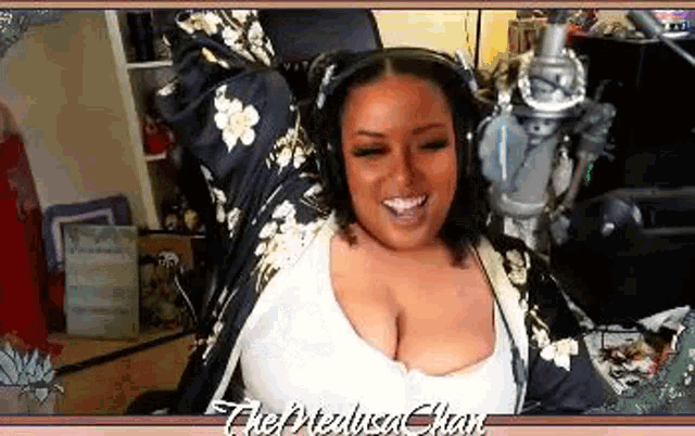 a woman wearing headphones is sitting in front of a microphone and smiling .