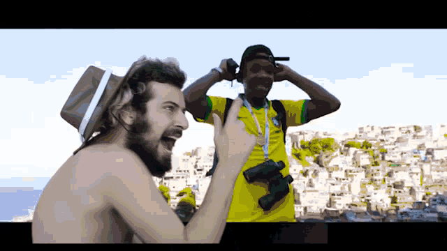 a man in a yellow shirt with a medal around his neck stands next to another man