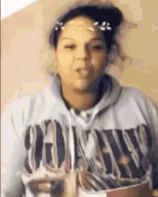 a woman is wearing a hoodie and a hat and making a funny face .