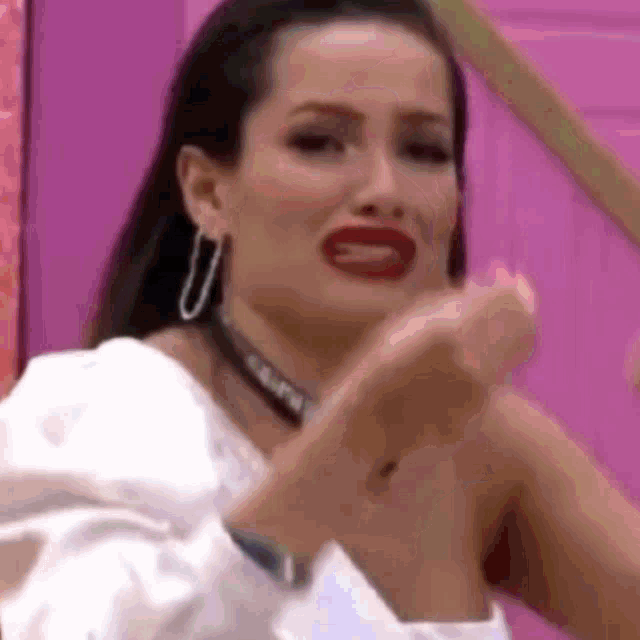a woman in a white shirt and red lipstick is making a funny face .