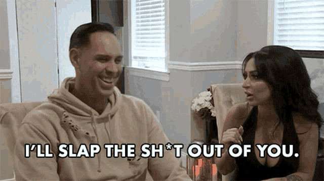 a man and woman are sitting at a table and the man is saying i 'll slap the sh * t out of you
