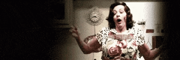 a woman in a floral dress is standing in a dark room with her arms outstretched and a clock in the background .