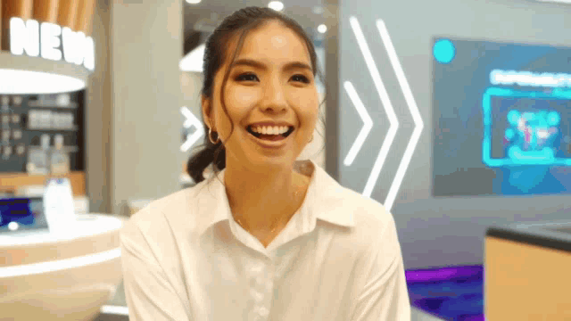 a woman laughs in front of a sign that says new
