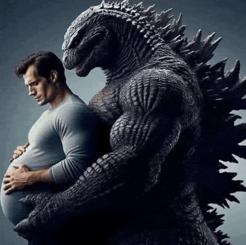 a man is holding a pregnant belly next to a statue of a monster .