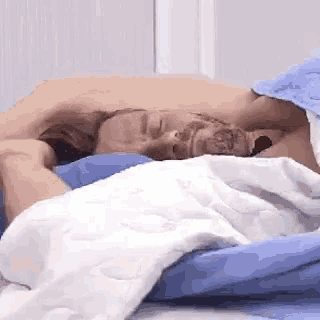 a man and a woman are laying in bed under a blue and white blanket .