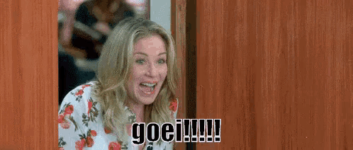 a woman is standing in a doorway with a surprised look on her face and the word goei written on the door .